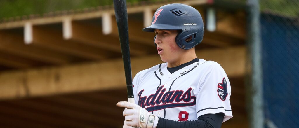 Elias Huber making contact with a pitch, swinging the bat with full extension during live game action