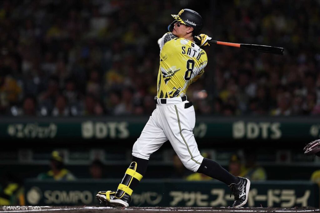 Hanshin Tigers batter wearing No. 8 follows through on a powerful swing during a night game.