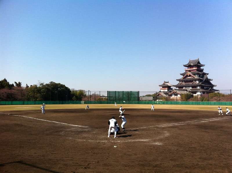 Fushimi Momoyama Stadium baseball field in Kyoto with castle-like architecture beyond the outfield