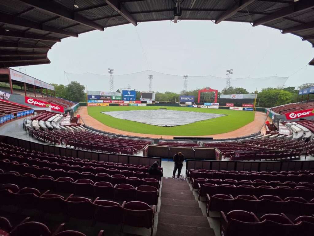 Rain tarp covers the infield at Estadio Julián Javier in the Dominican Republic during the October 2026 LIDOM rain delays.