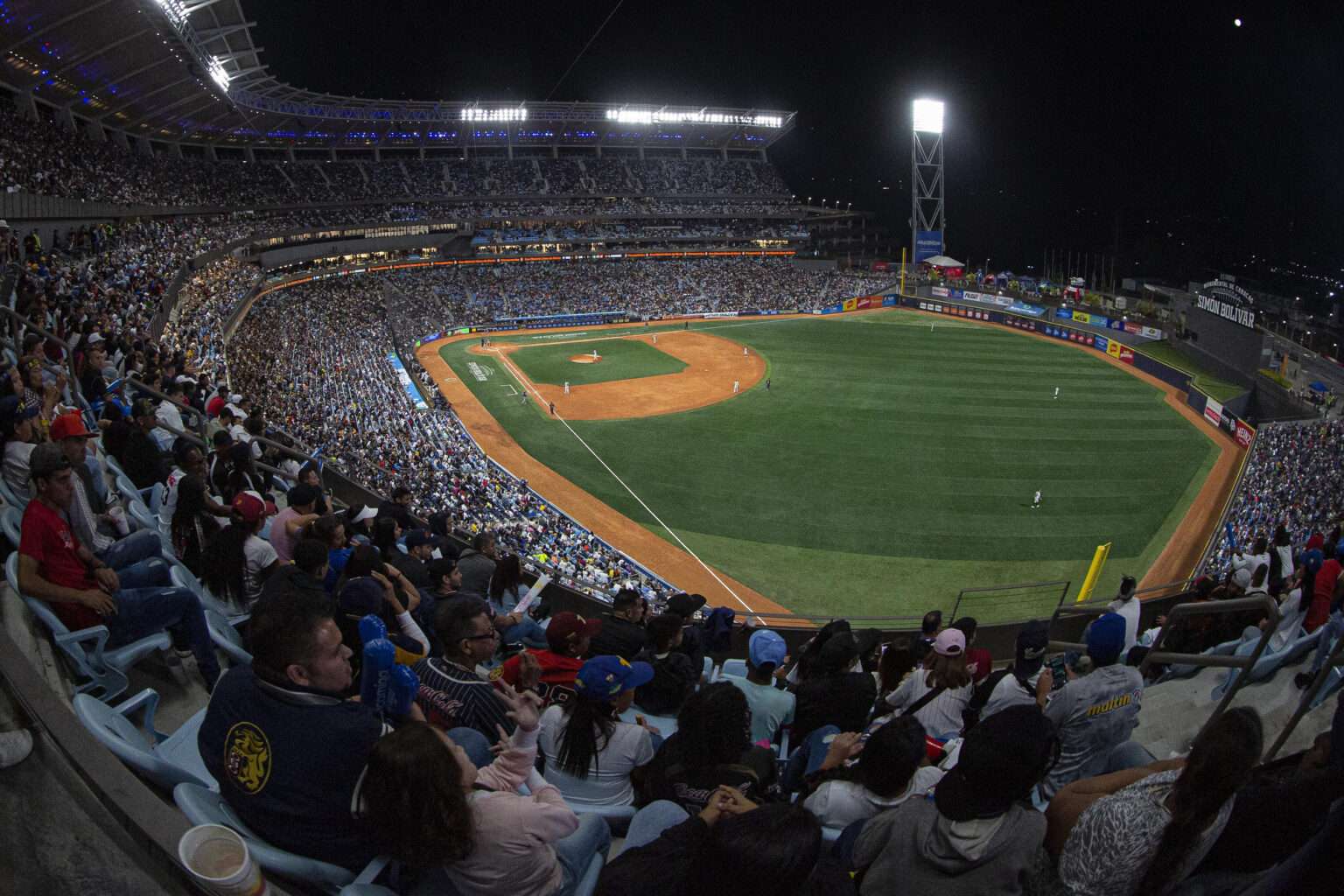 A packed Estadio Monumental Simón Bolívar in Caracas during the October 24, 2026 LVBP rivalry game between Leones del Caracas and Navegantes del Magallanes