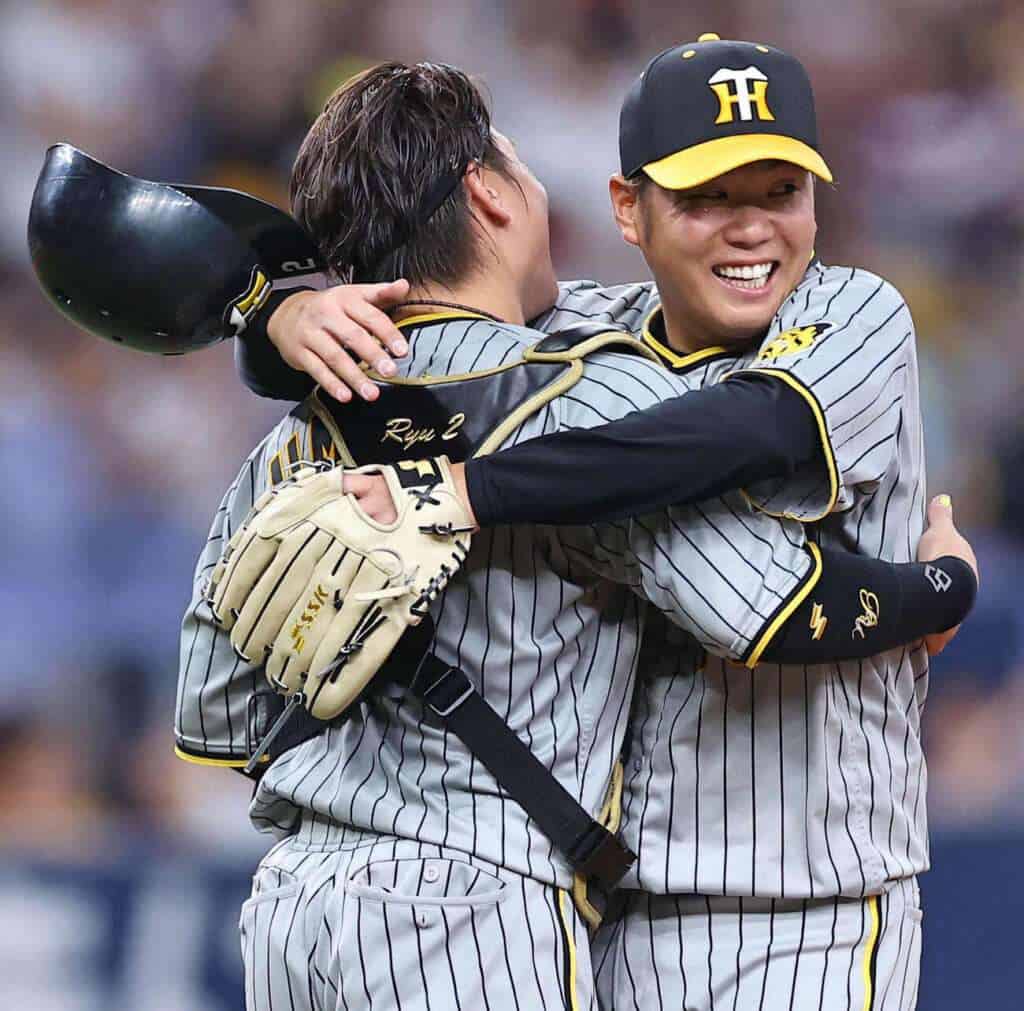 Yu Nishi and catcher Ryutaro Umeno embrace on the mound for the Hanshin Tigers